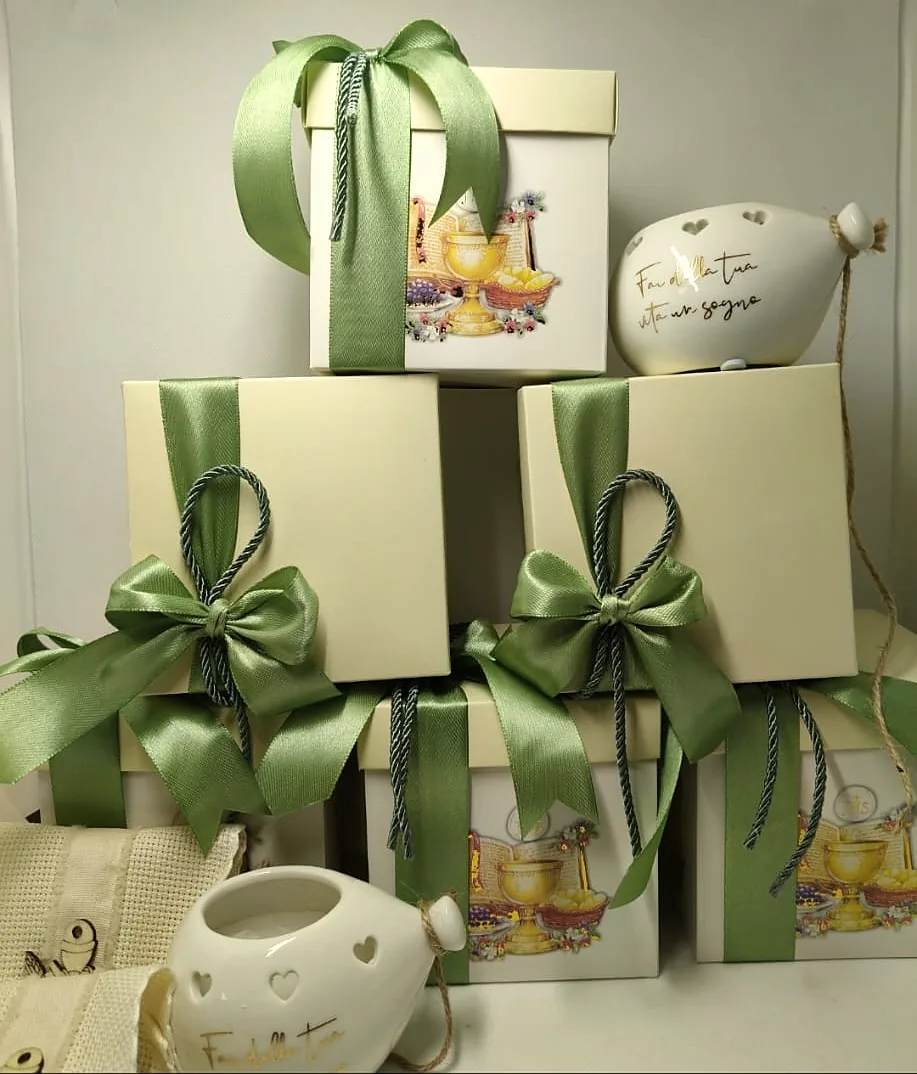 Scatole Karisma color avorio con fiocchi salvia, impilate accanto a piccole ceramiche