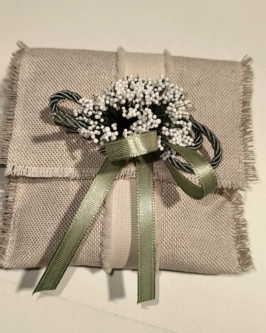 Bustina Karisma in lino sfrangiato con fiocco in raso salvia, cordoncino e mazzolino di fiori bianchi